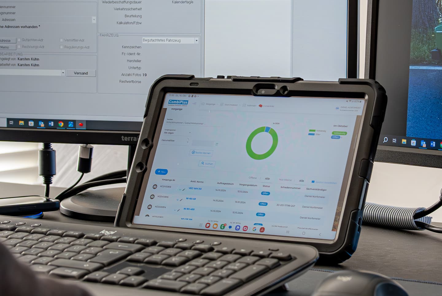 Ein moderner Arbeitsplatz in einem Kfz-Sachverständigenbüro, ausgestattet mit einer hybriden Softwarelösung. Im Vordergrund befindet sich ein Tablet in einer robusten Hülle, auf dem die Software „CombiPlus Online“ geöffnet ist. Die Benutzeroberfläche zeigt eine Übersicht mit einem grünen Kreisdiagramm und Daten zu Vorgängen. Im Hintergrund sind zwei Monitore zu sehen, auf denen „CombiPlus Professional“ läuft. Beide Softwarelösungen arbeiten zusammen als „CombiPlus Hybrid“, was die nahtlose Integration und Effizienz digitaler Arbeitsprozesse in der Kfz-Schadenbegutachtung unterstreicht. Eine Tastatur und eine Maus vervollständigen die professionelle Arbeitsumgebung.
