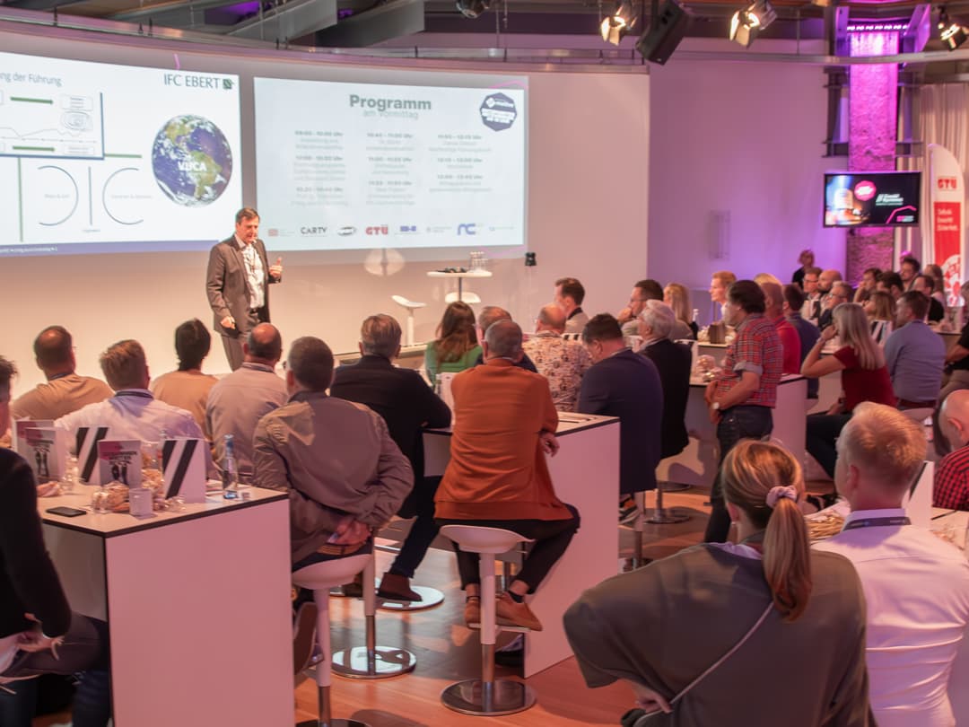  Das Bild zeigt eine Szene von eurem letzten CombiBildungsBuffet, bei dem ein Speaker auf der Bühne vor einem Publikum spricht. Die Veranstaltung scheint in einer professionellen und inspirierenden Atmosphäre mit interaktiven Elementen und Networking-Möglichkeiten stattgefunden zu haben.
