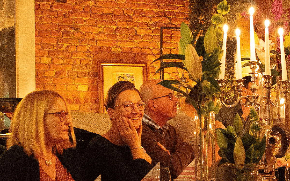 Acoll Busche, Christian Schmidt und Maren Sundermeyer vom CombiTeam bei einem festlich dekorierten Abendessen mit Kerzenschein – eine gemütliche Atmosphäre im Schein der Kerzen und vor rustikaler Backsteinwand.