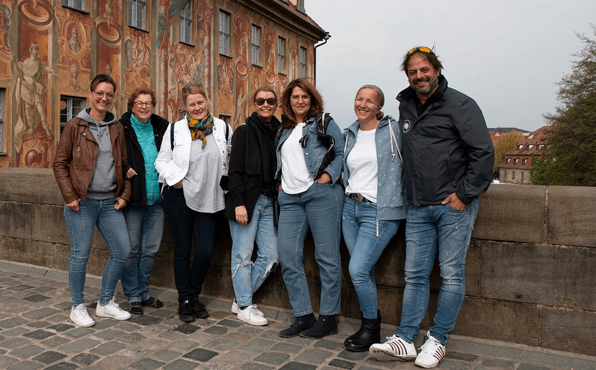 Das CombiTeam posiert gut gelaunt vor dem prachtvoll bemalten Alten Rathaus in Bamberg – ein starkes Team in historischer Kulisse, das Gemeinschaft und Lebensfreude ausstrahlt.