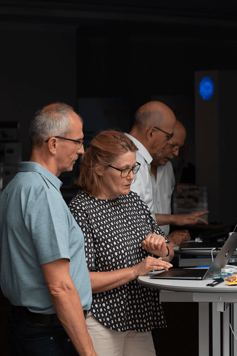 Maren Sundermeyer im Gespräch mit einem Besucher am CombiSystems-Messestand – konzentrierter Austausch an einem der Tische, im Hintergrund informiert Christian Schmidt weitere Interessierte. Ein professioneller Auftritt des CombiTeams.