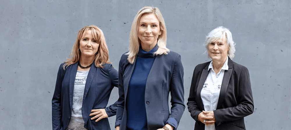 Victoria von Alkewitz (Mitte) mit zwei Kolleginnen – ein starkes Team in der Kfz-Schadenmanagements-Branche, das Kompetenz, Haltung und moderne Führungsstärke vereint.