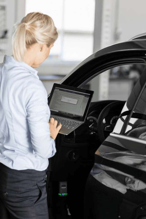 Victoria von Alkewitz mit Laptop beim Auslesen von Fahrzeugdaten – digitale Fahrzeugdiagnose als Teil moderner Gutachterarbeit im Kfz-Schadenmanagement.