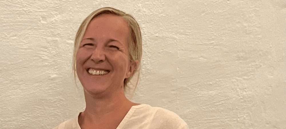 Swantje Mann vom CombiTeam steht vor einer strukturierten, hellen Wand und lächelt herzlich in die Kamera. Sie trägt ein schlichtes, helles Oberteil und strahlt Offenheit und Freundlichkeit aus.