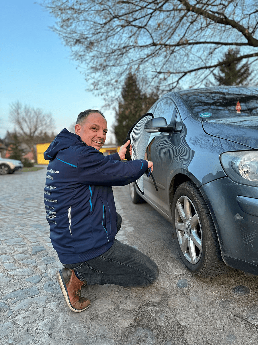 Mit voller Konzentration begutachtet Enrico Rehberg den Schaden an einem Fahrzeug. Ausgestattet mit Spezialwerkzeug und Messinstrumenten dokumentiert er präzise alle relevanten Details – ein Beispiel für sachverständige Arbeit auf hohem Niveau.
