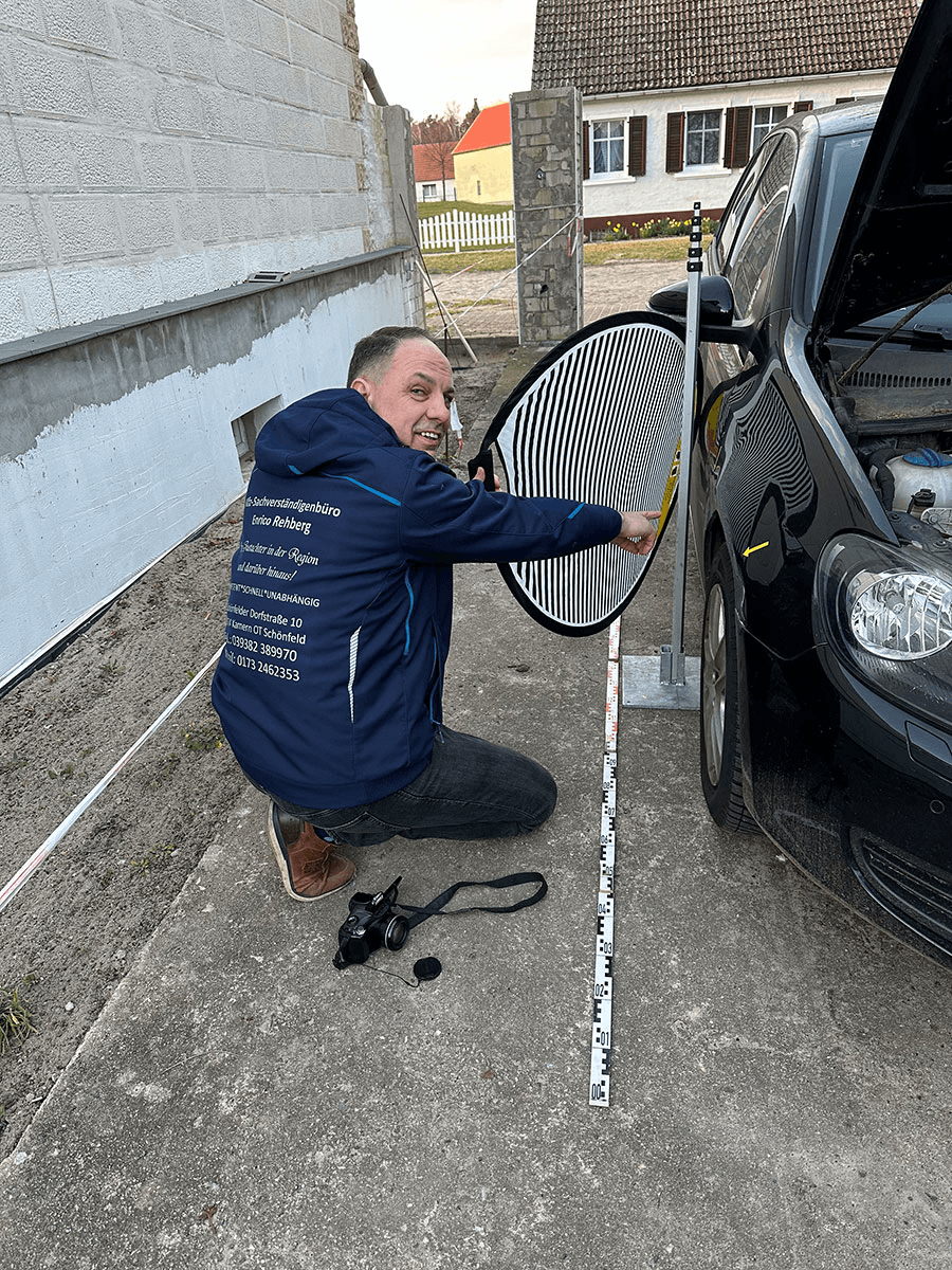 Enrico Rehberg vom Sachverständigenbüro Rehberg bei der präzisen Begutachtung eines Unfallschadens an einem Fahrzeug. Mit Lichtsichtschirm, Maßstab und Kamera dokumentiert er sorgfältig die Schadenshöhe und -tiefe für die spätere Gutachtenerstellung.